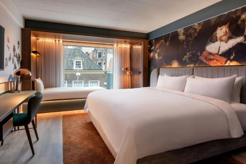 a bedroom with a large bed and a desk and a window at Renaissance Amsterdam Hotel in Amsterdam