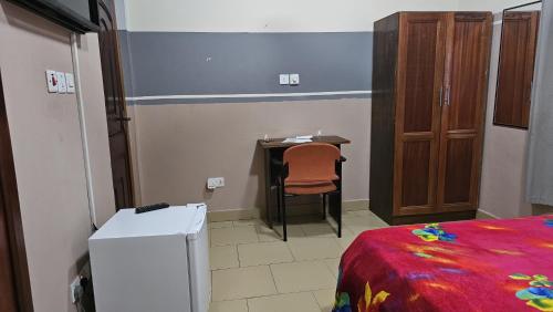 a room with a desk and a bed and a table at Queen's Hill Lodge in Oblogo