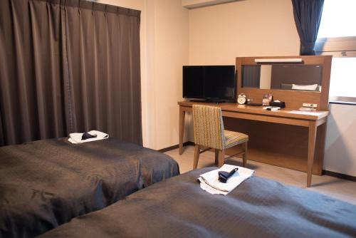 a hotel room with two beds and a desk with a mirror at Hotel Trad in Osaka