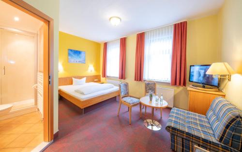 a hotel room with a bed and a tv at Hotel Stadt Suhl in Zella-Mehlis