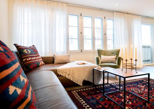 un soggiorno con divano, tavolo e finestre di Apartment Marmotta a Andermatt