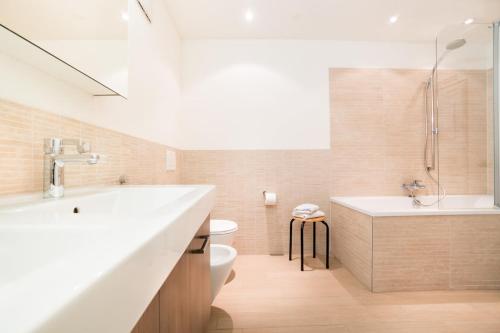 un bagno con lavandino, vasca e WC di Apartment Marmotta a Andermatt