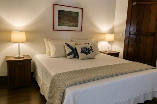 a bedroom with a large white bed with two lamps at 120 Hotel & Beach Club in Guarujá