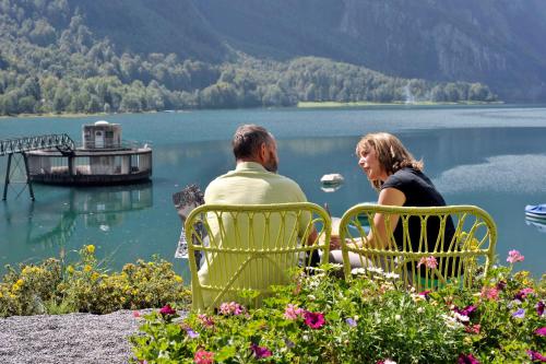 a man and woman sitting in chairs overlooking a lake at Hotel Rhodannenberg AG in Glarus
