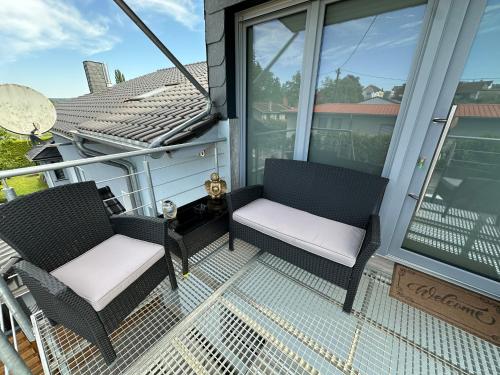 a balcony with two chairs and a table at Große Ferienwohnung Gästehaus NEUBAU Merzig 120m2 in Merzig
