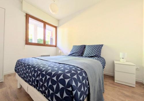 a bedroom with a bed with a blue comforter and a window at T2 near lake,pool,terrace in Soustons