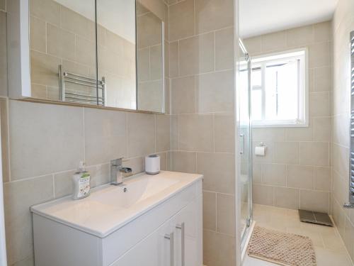 ein weißes Badezimmer mit Waschbecken und Spiegel in der Unterkunft Sunnyfield Cottage in Coulsdon