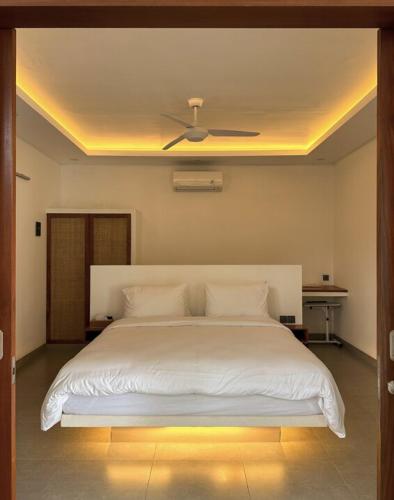 a bedroom with a white bed with a ceiling fan at Casa De Cuentos Bali in Denpasar