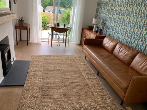 a living room with a brown leather couch and a table at 2 Bed-Sleeps 4-Parking-Pets-10 min walk to Beach in Falmouth