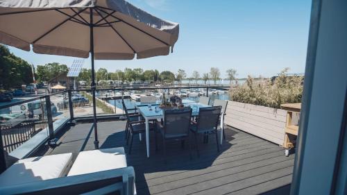 a deck with a table and chairs and a view of a marina at Intens Genieten aan het Sneekermeer in Offingawier