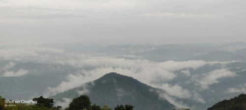 a mountain covered in clouds in the sky at Skylark Homestay Panchalimedu in Pīrmed