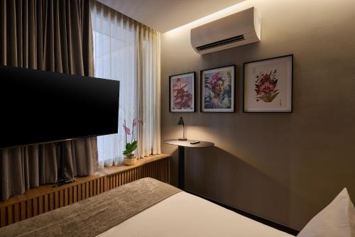 a hotel room with a bed and a flat screen tv at Calle Flora Hotel by Jalo in Medellín