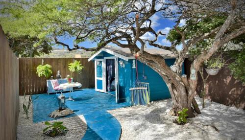 a blue house with a tree in the yard at Mammaloe in Oranjestad