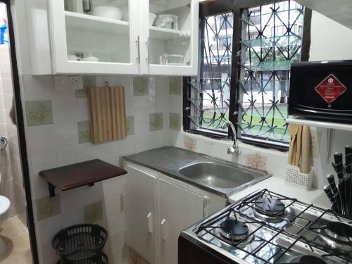 Una pequeña cocina con estufa y fregadero. en Jaycee Holdings Properties, en Mombasa