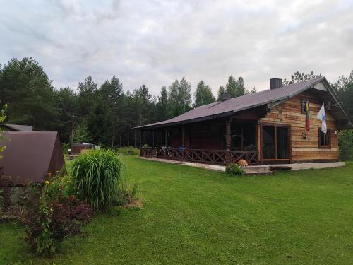a log cabin in a field of grass with trees at Piglet house in Alytus