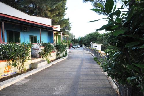 an empty street next to a blue building with trees at Villaggio Elisena in Vieste
