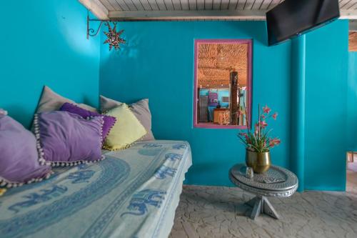 a blue room with a bed with purple pillows at Mammaloe in Oranjestad