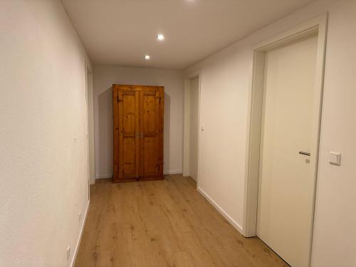 an empty hallway with a wooden door and wooden floors at Große Wohnung am Segelflugplatz in Marpingen