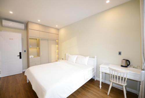 a white bedroom with a white bed and a desk at Liséa Wonderland Novaworld Hồ Tràm - Spacious and Cosy Entire Villa by the beach in Xuyên Mộc