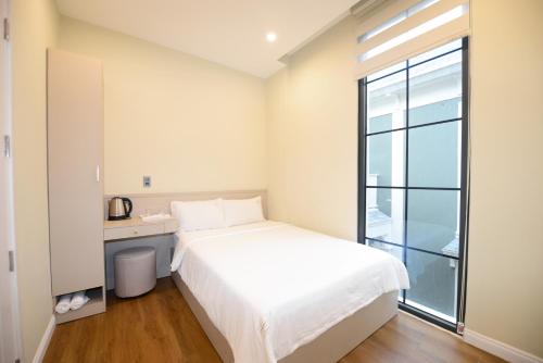 a bedroom with a white bed and a window at Liséa Wonderland Novaworld Hồ Tràm - Spacious and Cosy Entire Villa by the beach in Xuyên Mộc