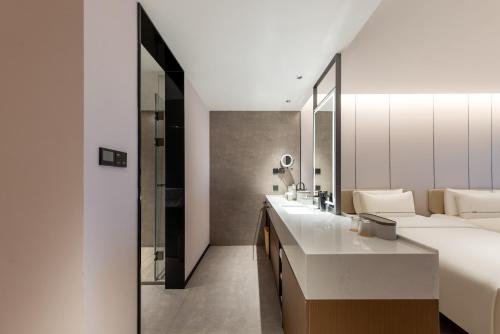 Atour Hotel Suzhou Jinji Lake East Park High-Speed Rail Station في سوتشو: غرفة فندقية مع سرير وحمام