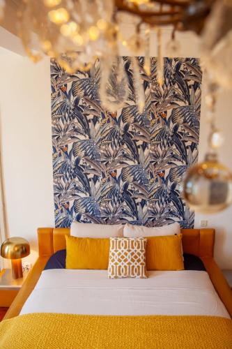 a bed with yellow pillows and a blue and white wallpaper at Manoir d Armagnac in Courrensan