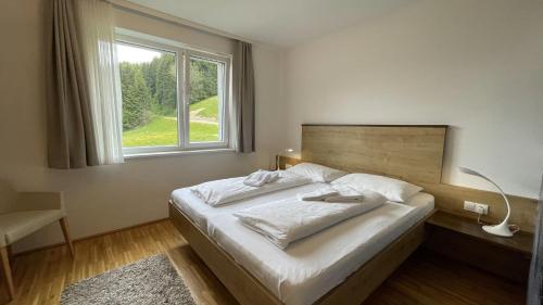 ein Schlafzimmer mit einem Bett mit einem großen Fenster in der Unterkunft Apartmány ALPINE LIVING Haus - Schladming in Haus im Ennstal