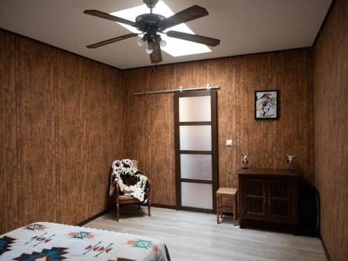 a bedroom with a ceiling fan and a chair at Appartement rénové sur le thème du Far West in Soyaux
