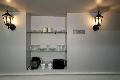 a kitchen with two lights and shelves with glasses at Eden Garden By Jolly Homes in Pasumalai