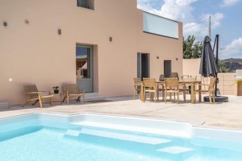 a villa with a pool and a table and chairs at Roots Villa in Skinés