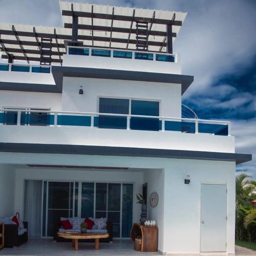a white house with a balcony on top of it at Red Heart 3 Bedrooms Villa in Sosua