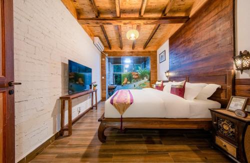 a bedroom with a large bed and a wooden ceiling at Dai House in Xishuangbanna Village in Menghan