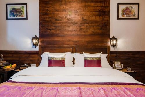 a bedroom with a large bed with wooden walls at Dai House in Xishuangbanna Village in Menghan