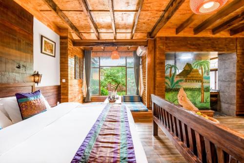 a bedroom with a large bed and a large window at Dai House in Xishuangbanna Village in Menghan