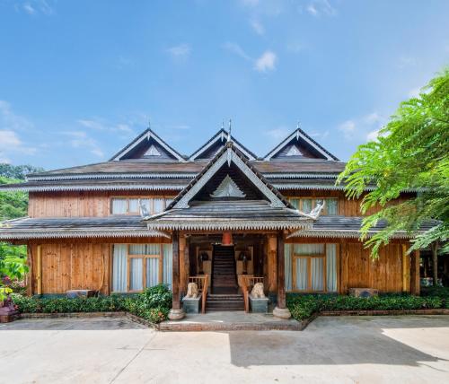 a large wooden house with a staircase in front of it at Dai House in Xishuangbanna Village in Menghan