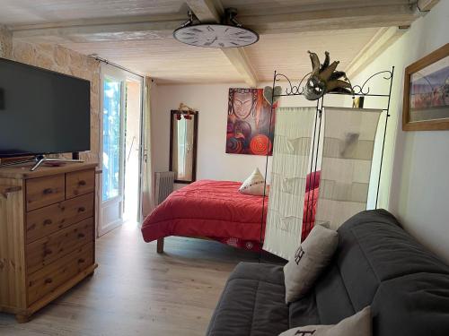 un salon avec un lit et une télévision dans l'établissement Coquelicot, à Montagnac
