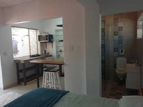 una camera con letto e una cucina con tavolo di The Seabird Cottage a Gqeberha