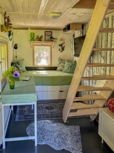 a tiny house with a staircase and a bed at Small Cabin With Outdoor Kitchen By Forest Stream in Trollhättan