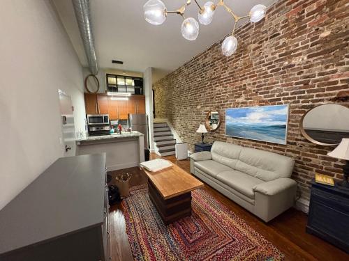 a living room with a couch and a brick wall at Downtown Charleston Condo in Charleston