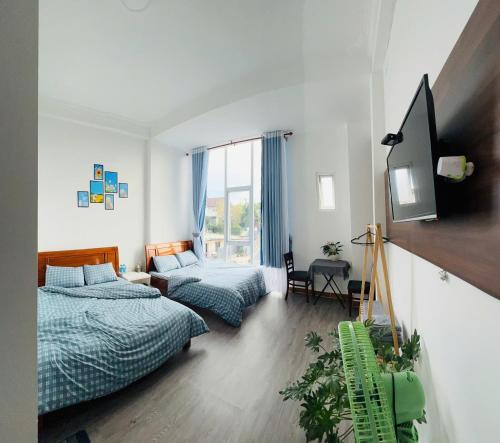 Xuan AnにあるDaLatXanh Houseのベッド2台とテレビのある寝室