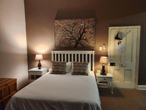 a bedroom with a bed with two lamps and a tree painting on the wall at Spes Bona guesthouse in Colesberg