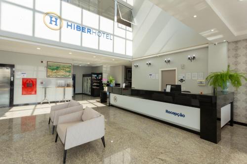 a hotel lobby with a reception desk and chairs at Hiber Hotel - Acesso a Chapecó in Chapecó