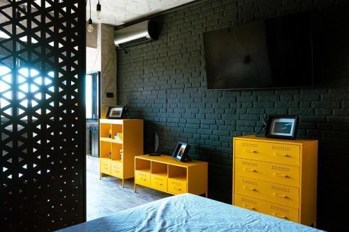ein Schlafzimmer mit gelben Kommoden und einem Flachbildfernseher in der Unterkunft The Industry in Galaţi