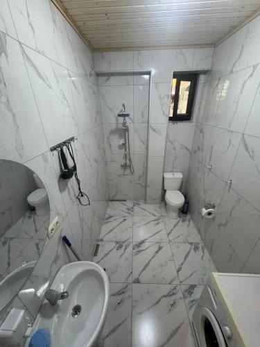 a white bathroom with a sink and a toilet at Tsikhisdziri Home in Ts'ikhisdziri