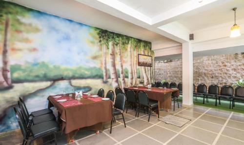 a dining room with tables and chairs and a large painting at Treebo Komfort Suites, 3 Km From Mysore Palace in Mysore