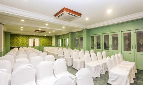a room with white chairs and green walls at Treebo Komfort Suites, 3 Km From Mysore Palace in Mysore