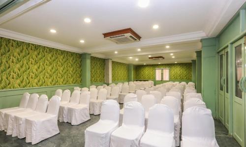 a room with white chairs and green walls at Treebo Komfort Suites, 3 Km From Mysore Palace in Mysore