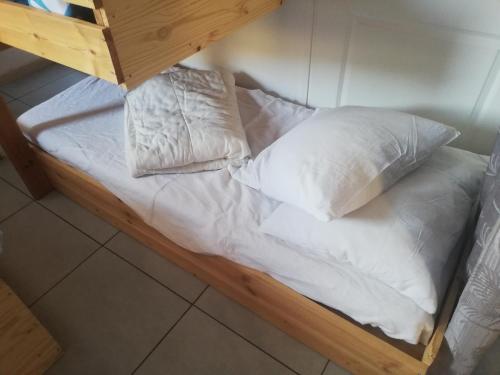 a bed with white sheets and pillows on it at Studio au pied des pistes in Bagnères-de-Bigorre