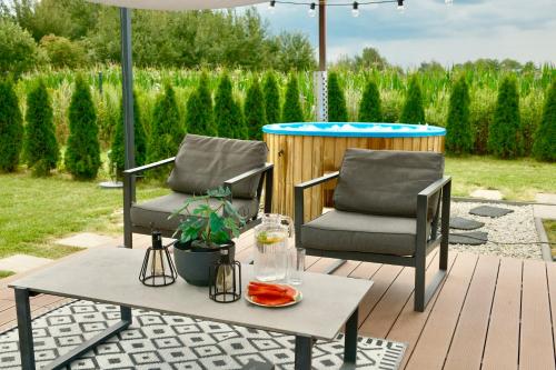 two chairs and a table under an umbrella on a patio at Dolina Słońca obok Suntago - nowoczesne domy z jacuzzi in Benenard