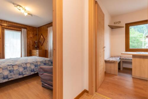 a bedroom with a bed and a desk and a window at Appartamento Alba sulle Dolomiti in Falcade